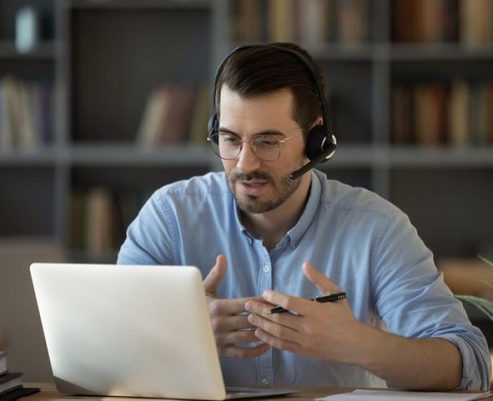 Confident man teacher wearing headset speaking, holding online lesson